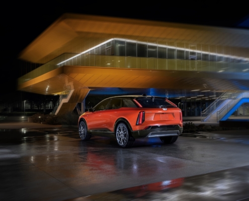 A rear 3/4 view of the 2025 Cadillac OPTIQ in Monarch Orange.